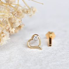 "This unique heart shaped stud is crafted in solid 14k or 18k gold with a natural diamond inside. This elegant piercing stud is available in multiple closure options for different piercings like nose, ear, tragus, cartilage, lobe etc. *  Gold: 14k / 18k Solid Gold  *  Gold Colour: Yellow / Rose / White  *  Gold Wt.: ~1.3gms (14kt) *  Gemstone: Natural Genuine Diamond *  Diamond Wt.: ~0.015 Ct *  Color/Clarity: H-I, Vs-Si *  Dimension: ~6 x 5.6mm  * Authenticity Check: This stud will be marked for gold and will come with EGL (or equivalent) Certification PLEASE NOTE: - White gold CONTAINS NICKEL.  - Yellow and Rose Gold NICKEL FREE.  - White and Yellow Gold pieces are RHODIUM PLATED. Please mention if you prefer otherwise.  - Rose Gold pieces are NOT RHODIUM PLATED.  PACKAGING: > Each packa Gold Heart Earrings Diamond Cut Gift, 14k Gold Diamond Cut Heart Earrings, 14k Gold Heart Earrings With Diamond Cut, 14k Yellow Gold Heart Earrings With Diamond Cut, Diamond Cut Heart Earrings For Gift, Gift Heart Earrings With Diamond Cut, Yellow Gold Diamond Heart Earrings Gift, Dainty Diamond Heart Earrings In Gold, Gold Diamond Heart Earrings In Dainty Style