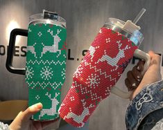 a person holding a cup with a christmas pattern on it and thermos in front of them