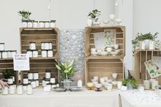 the table is covered with candles and other items for sale at an outdoor market stall