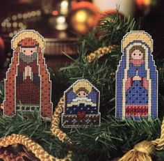 three cross stitch nativity ornaments hanging from a christmas tree