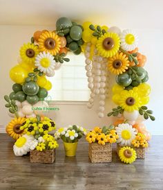 the balloon arch is decorated with sunflowers and greenery