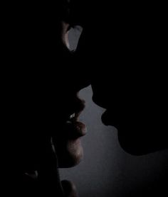 the silhouette of two people are facing each other