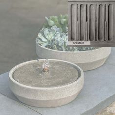 two cement planters with water coming out of them, one is grey and the other is black