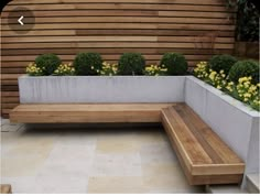 a wooden bench sitting next to a planter filled with yellow flowers