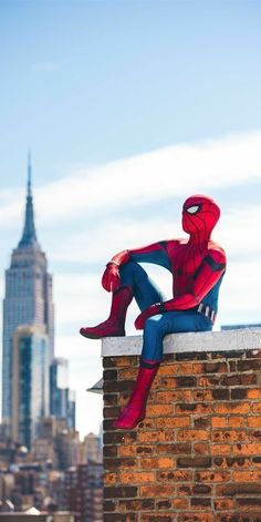 a spider man sitting on top of a brick wall