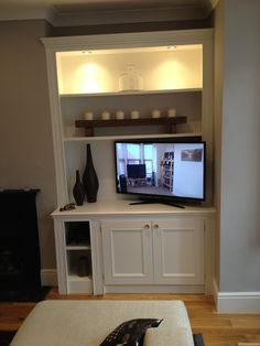 a flat screen tv sitting on top of a white entertainment center in a living room