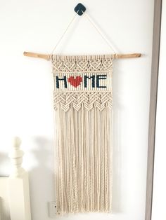 a macrame wall hanging with the word home written on it