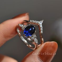 a person holding a ring with a blue stone in it