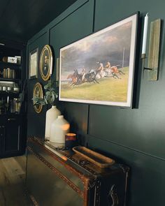 a painting hangs on the wall next to an antique trunk in a room with green walls