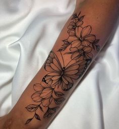 a woman's arm with flowers and leaves on the side of her body, in black ink