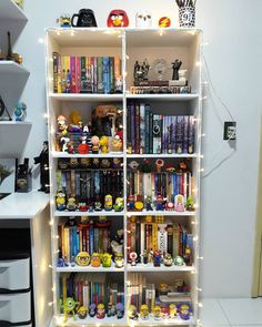 a book shelf filled with lots of books on top of a white floor next to a desk