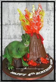 a birthday cake with a dinosaur and volcano on it