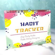 a spiral notebook with the words habit tracker on it, sitting on a white surface