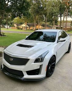 a white cadillac parked in front of a house