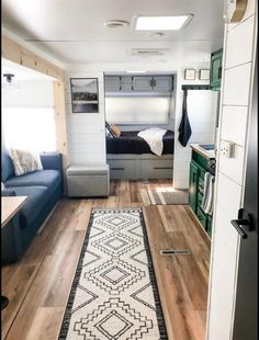 the interior of a tiny home with wood flooring and blue couches in it