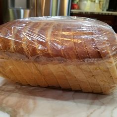 a loaf of bread wrapped in plastic sitting on top of a counter