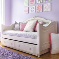 a white daybed with drawers underneath it in a purple and pink bedroom setting,