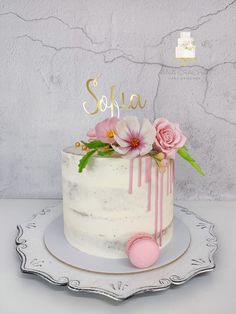 a white cake with pink flowers and the word sofia on top is sitting on a plate