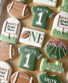 decorated cookies in the shape of football jerseys and numbers are arranged on a tray for display