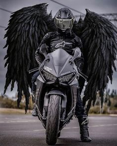 a man riding on the back of a motorcycle with black wings