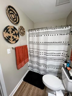 a white toilet sitting in a bathroom next to a shower curtain and sink with red towels on it