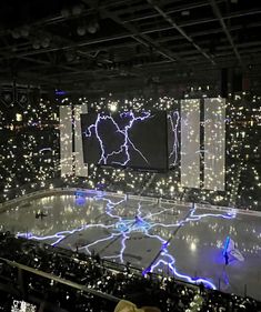 an ice rink is lit up with blue and white lights in the middle of it