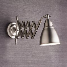 a wall mounted light on the side of a gray wall next to a white lamp