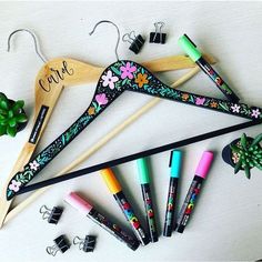 a wooden hanger that has some pens and markers on it next to other items