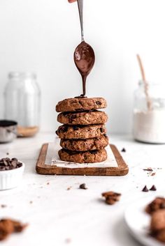 chocolate chip cookies stacked on top of each other and being drizzled with chocolate