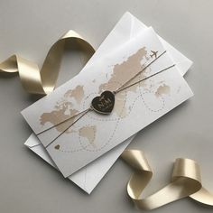 a card with a heart on it next to some gold ribbon and a world map