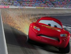 the character cars are racing around in front of an empty race track with fireworks coming out of them