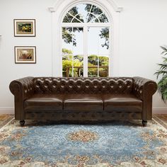 a brown leather couch sitting on top of a blue rug in front of a window