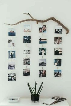 a white table topped with pictures and a plant next to a wall mounted photo frame