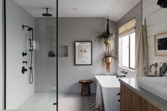 a bathroom with a sink, mirror and shower in it's center wall next to a window