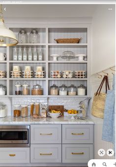 a kitchen with white cabinets and lots of food on the counter top in front of it