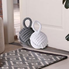 two roped baskets sit on the floor next to a door mat and potted plant