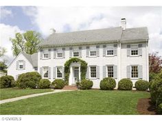 a large white house sitting on top of a lush green field