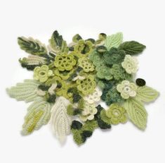 crocheted leaves and flowers are arranged on a white surface