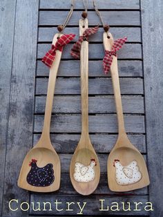 three wooden spoons decorated with chicken and rooster appliques on wood planks