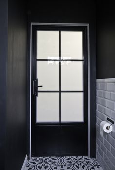 a black and white tiled bathroom with a glass door