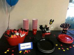 mickey mouse party decorations on a black tablecloth with red and blue plates, cups, and balloons