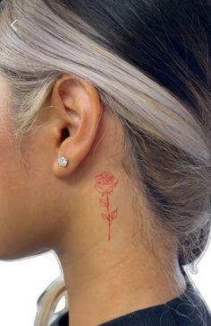 a woman with a red rose tattoo on her left side behind her ear and behind her ear is a small diamond