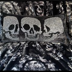 a black and white pillow with three skulls on the front, one is made out of silver sequins