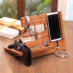 a cell phone and other items are on a table next to a wallet, watch, bracelets, and ring