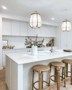 a kitchen with white countertops and stools next to an island in the middle