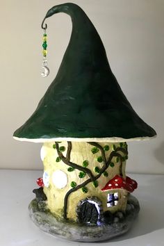 a green gnome's hat on top of a small house with trees and mushrooms