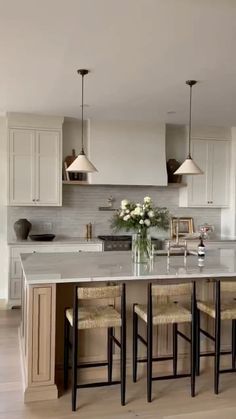 a kitchen island with four stools in front of it and flowers on the counter