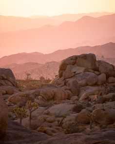 the sun is setting over some rocks and mountains