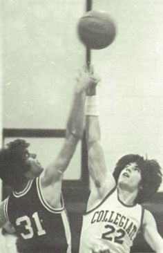 two men are playing basketball in an old black and white photo, one is reaching for the ball