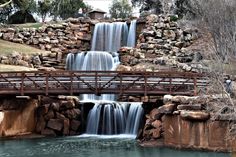 a bridge over a river with a waterfall in the background